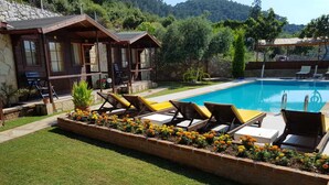 A pool area with lounge chairs and a flower bed.