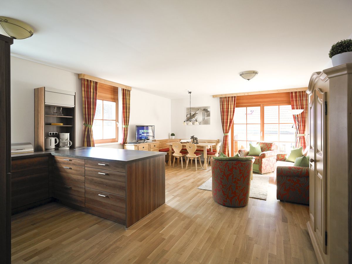 Une cuisine moderne avec des meubles en bois, un îlot central et un coin repas comprenant une table et des chaises.
