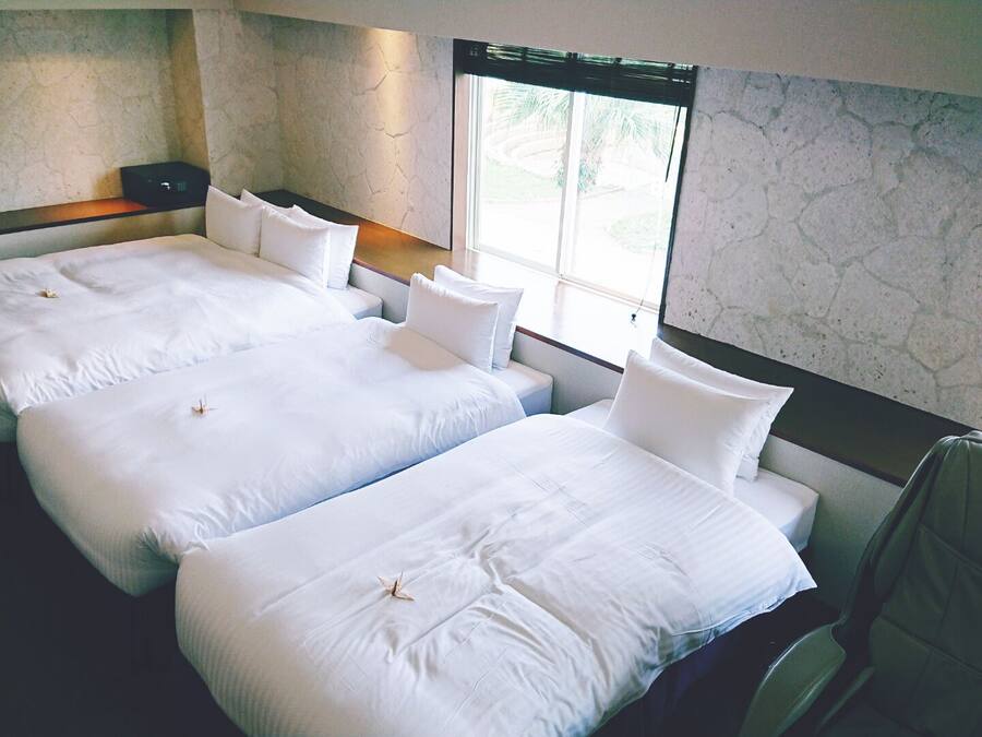A hotel room with two beds, a chair, and a large window.