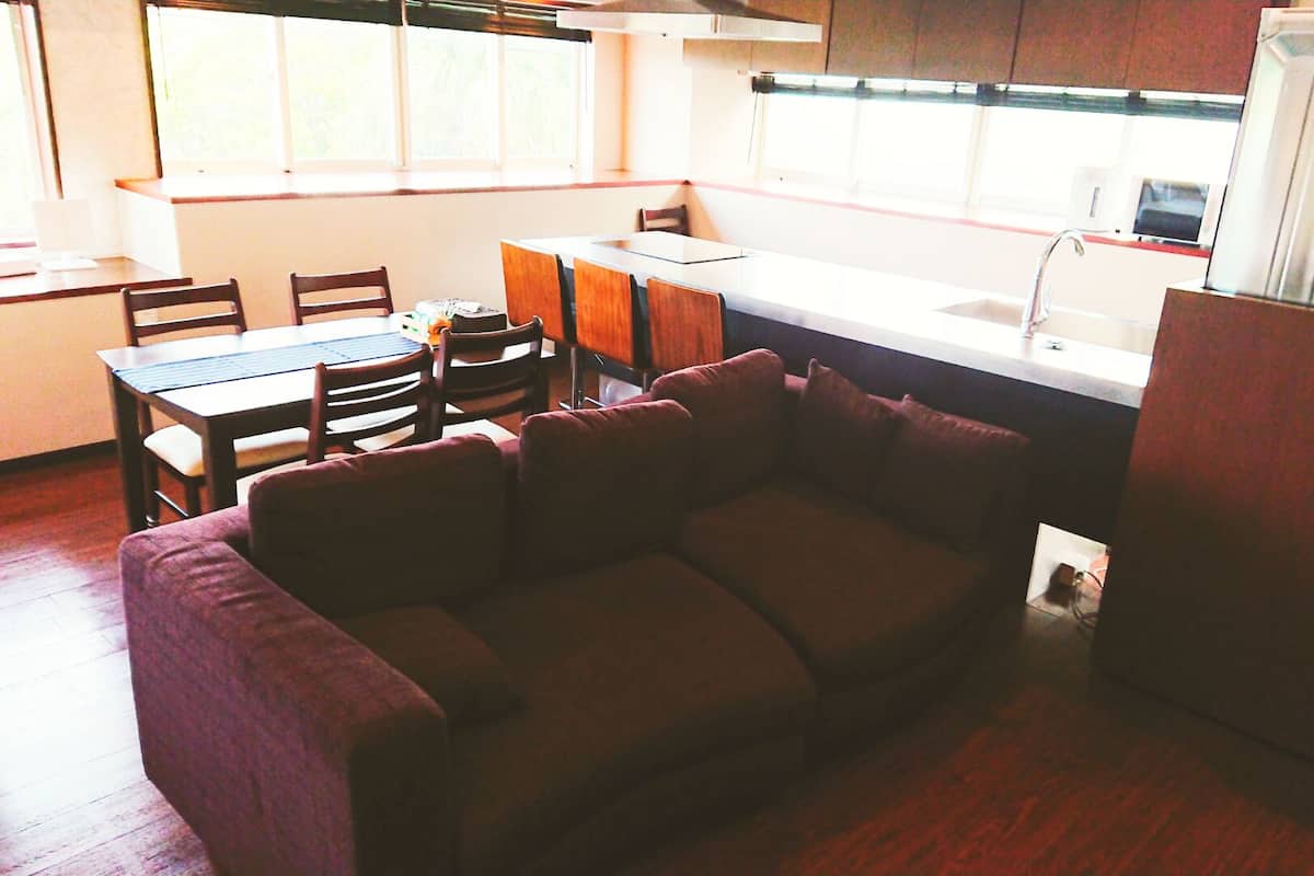 A compact kitchen with a dining area, a sofa, and a refrigerator.