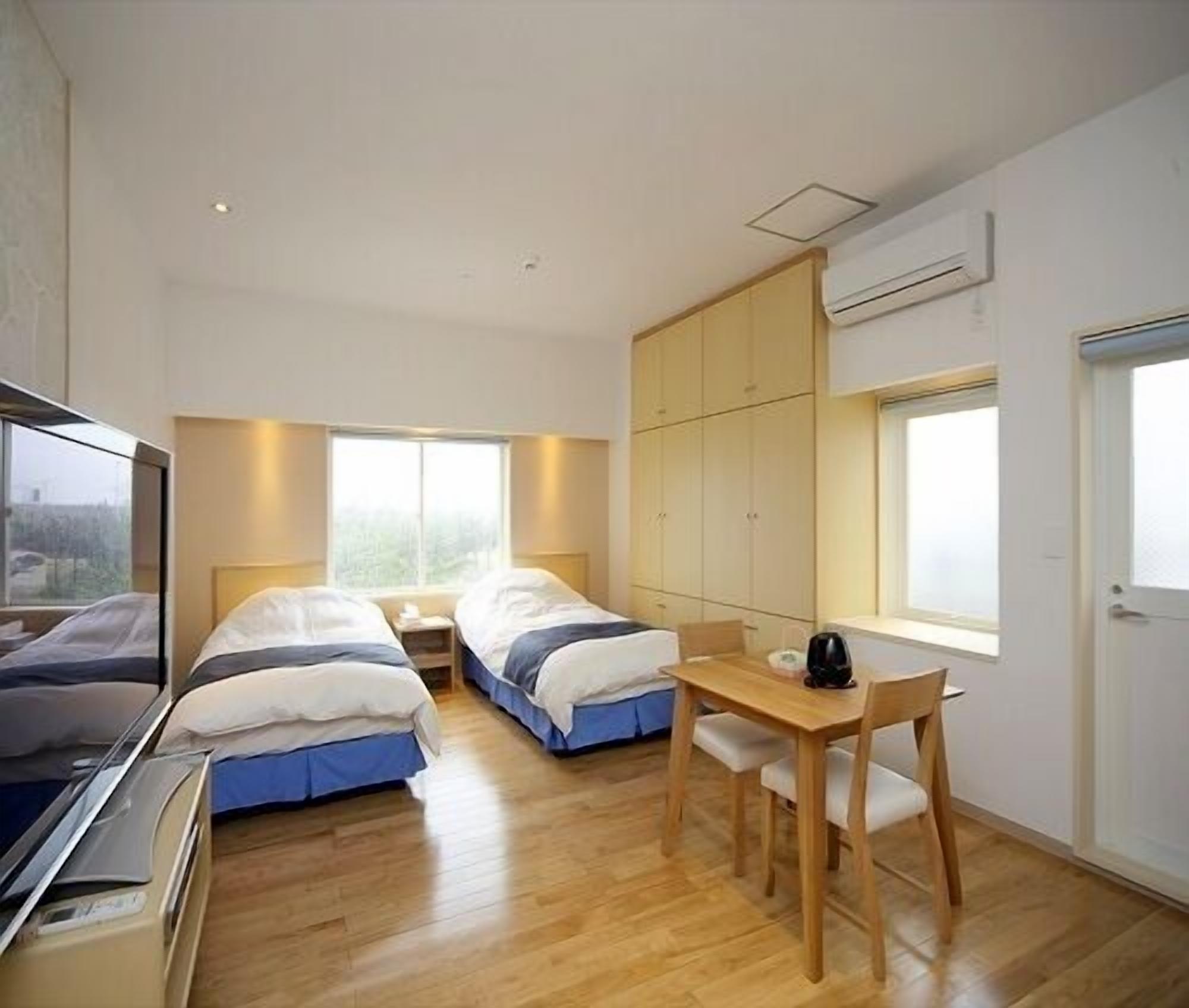 Una habitación de hotel con dos camas, un escritorio de madera, una silla y un televisor.