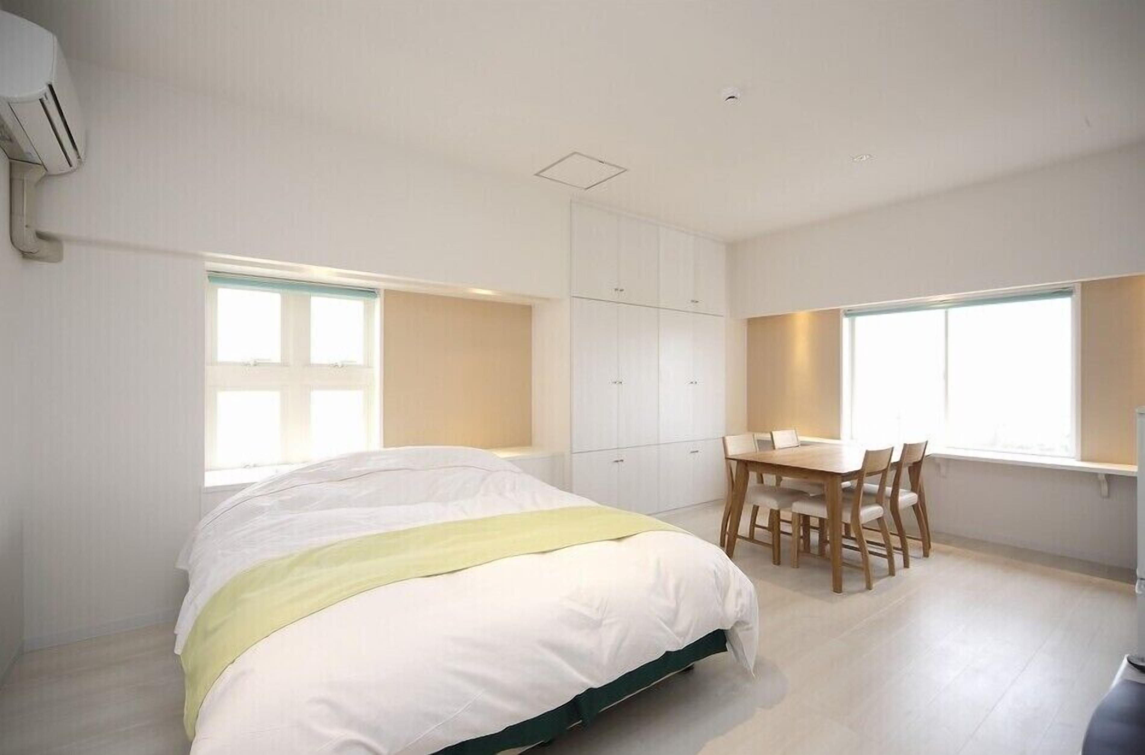 Un dormitorio con cama, escritorio y silla, y una ventana con vistas.