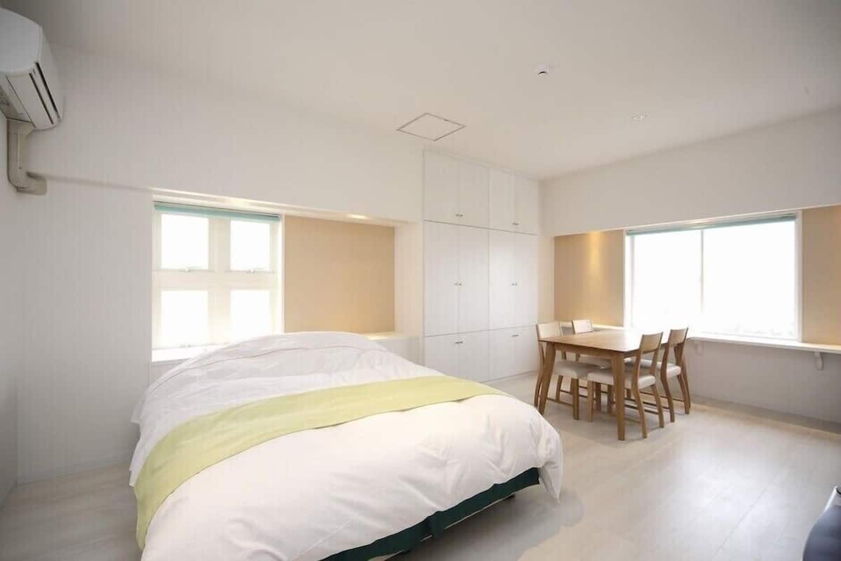 A bedroom with a bed, a desk, and a chair, and a window with a view.