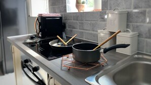 Eine Küche mit Herd, Töpfen, einer Kaffeemaschine sowie Zucker und Tee.