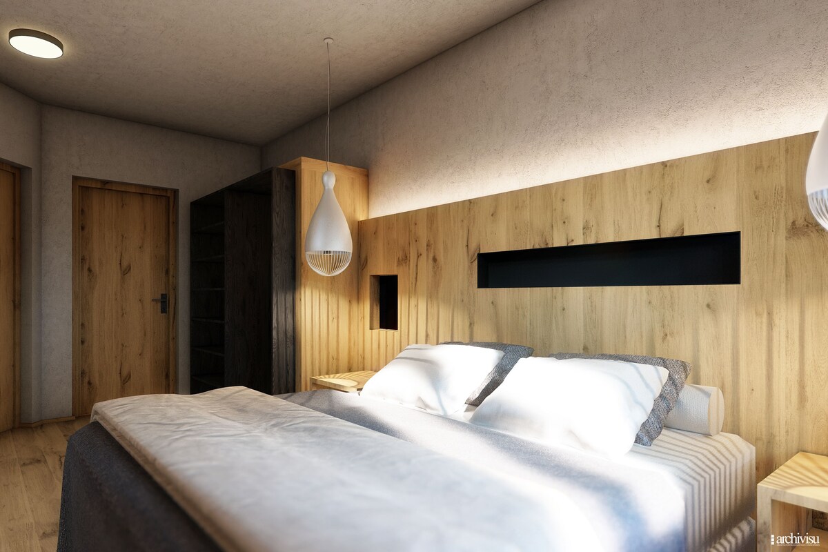 A bedroom with a bed, wooden walls, a hanging light fixture, and a small shelf.