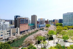 Un paisaje urbano con un río, flores de cerezo y edificios modernos.