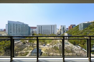Vista desde un balcón sobre un paisaje urbano con edificios modernos y una zona verde.