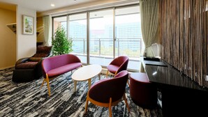 Et moderne hotelværelse med et stort vindue, en sofa, et sofabord og et fjernsyn.