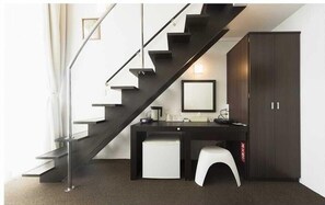 A modern room with a dark staircase, a desk, a chair, and a wardrobe. - Wires Hotel Onna Clipper Okinawa Base (Onna)