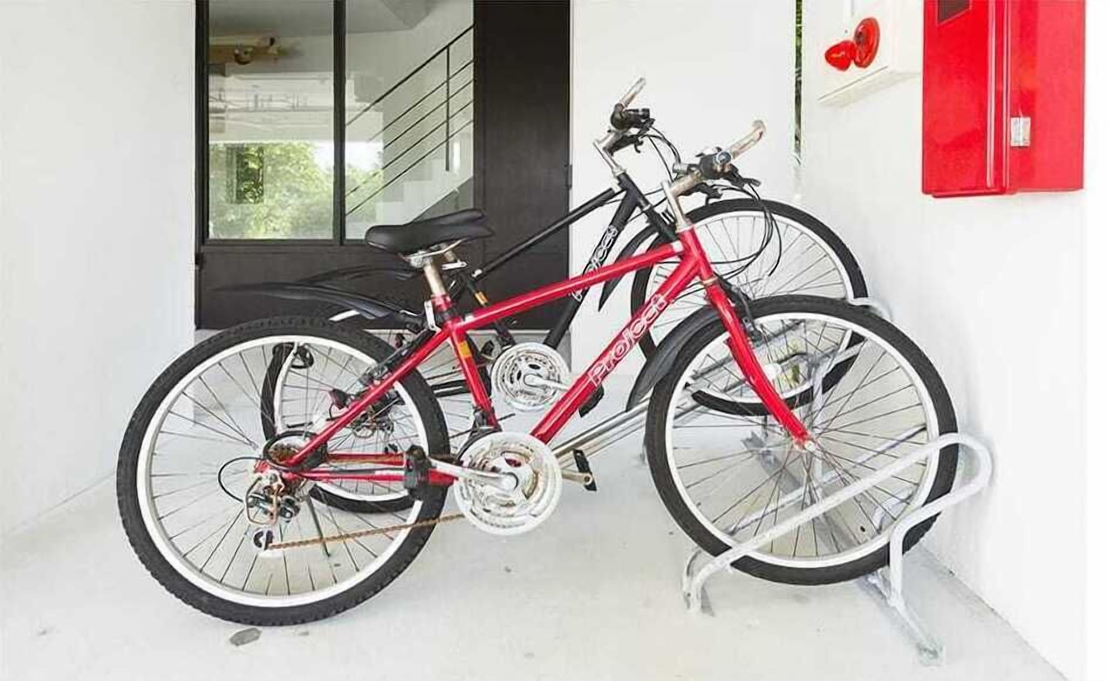 En röd cykel står parkerad inomhus med ett vitt cykelställ.