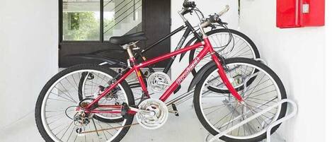 En röd cykel står parkerad inomhus med ett vitt cykelställ.