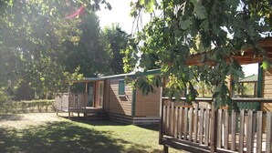 Une rangée de cabanes en bois, chacune dotée d’une véranda et donnant sur une aire de jeux clôturée.