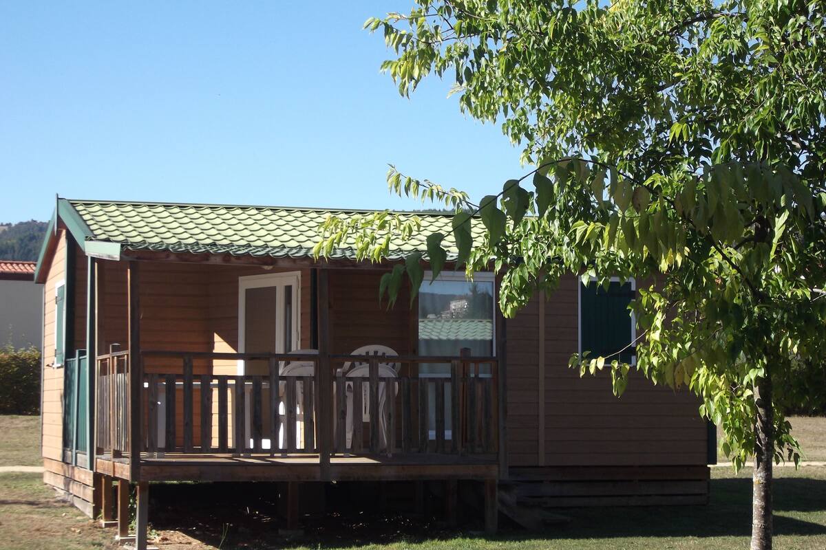 Une petite cabane en bois avec une véranda, une porte et une fenêtre.