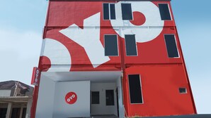 A building with a large red and white logo, a sign indicating 'OYO', and a door leading to an entrance. - OYO 682 Ceria Homestay Syariah (Semarang)