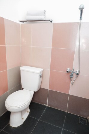 A bathroom with a toilet, a shower, and a shelf with a roll of toilet paper. - OYO 682 Ceria Homestay Syariah (Semarang)