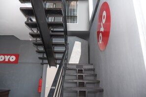 A staircase with a metal railing, a fire extinguisher, and a 'YOYO' sign on the wall. - OYO 682 Ceria Homestay Syariah (Semarang)