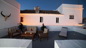 A rooftop patio with a white building, a bull skull decoration, and a small table with chairs. - Factory Rooms Tarifa - Hostel (Tarifa)