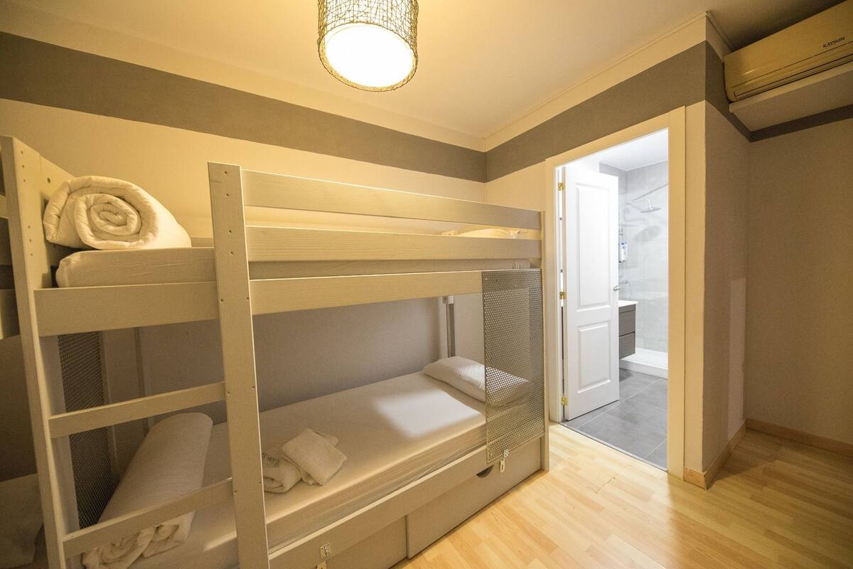A bunk bed room with a shower area visible through an open door.