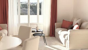 A modern living room with a sofa, armchairs, a small table, and a view of a cityscape through large windows. - Penthouse with Rome View, Balconies, Two Bathrooms & Metro (Roma)