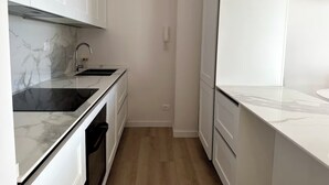 A modern kitchen with white cabinets, a marble countertop, and a built-in oven. - Penthouse with Rome View, Balconies, Two Bathrooms & Metro (Roma)