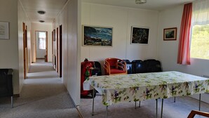 Et hotelværelse med en lang gang, et spisebord med stole, en brandslukker og kunst på væggene.