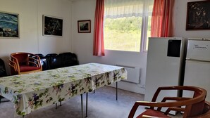 Et værelse med et spisebord, stole, et køleskab og et vindue med gardiner.