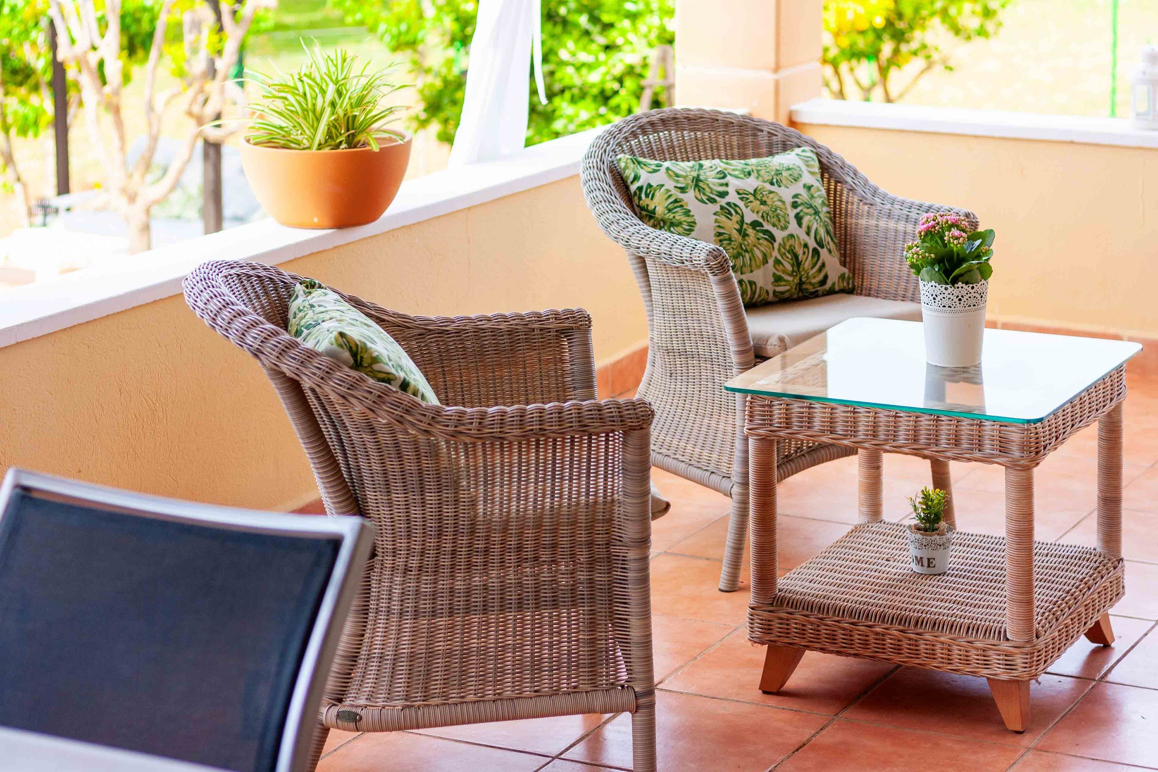A wicker chair with a cushion and a small table with a potted plant.