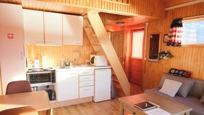A compact room with a kitchenette, a dining area, and a sofa.