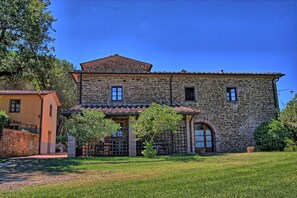 Un bâtiment en pierre avec un toit en tuiles, un petit porche et un jardin clos.