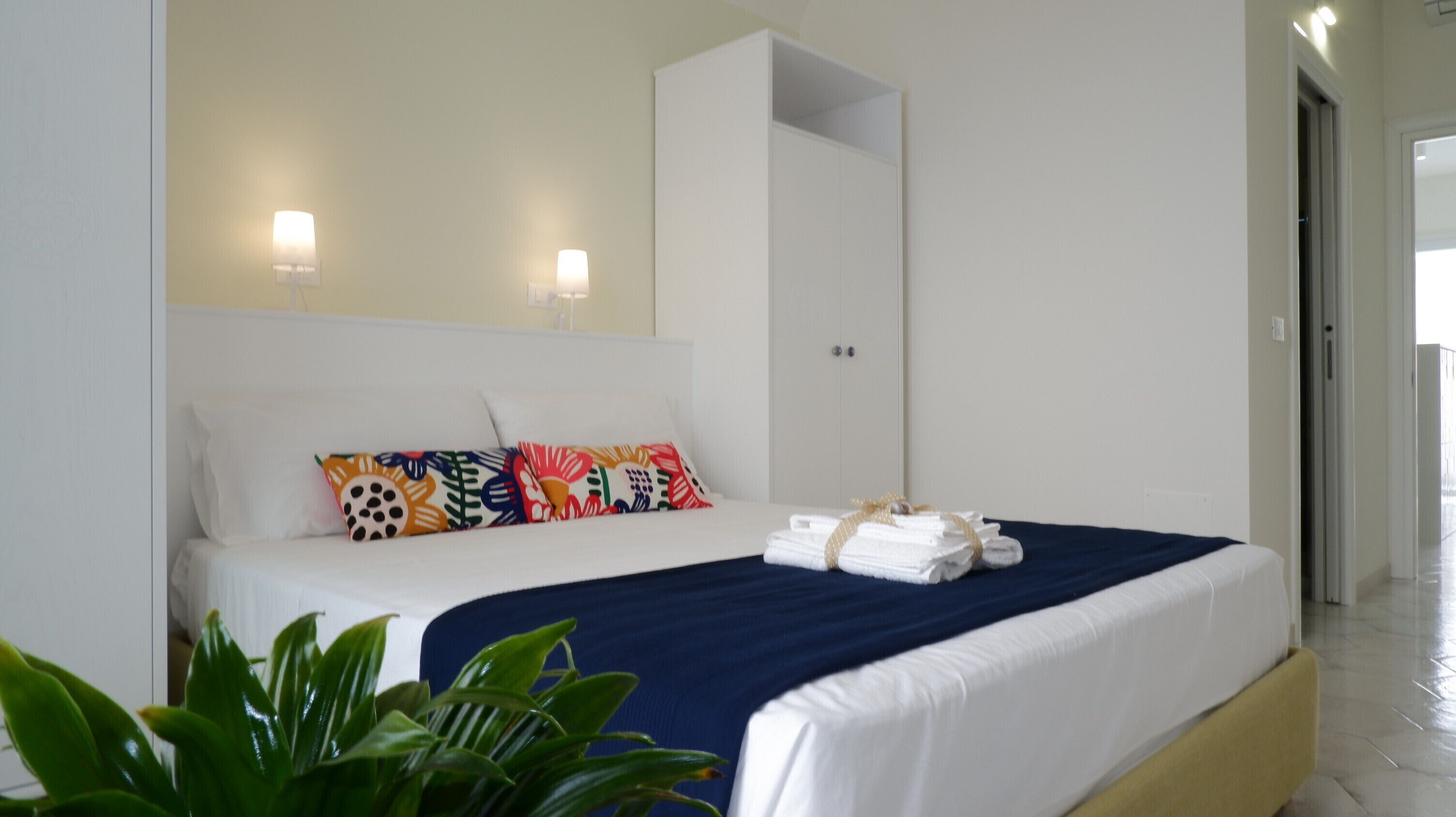A hotel room with a bed, a wardrobe, and a potted plant.