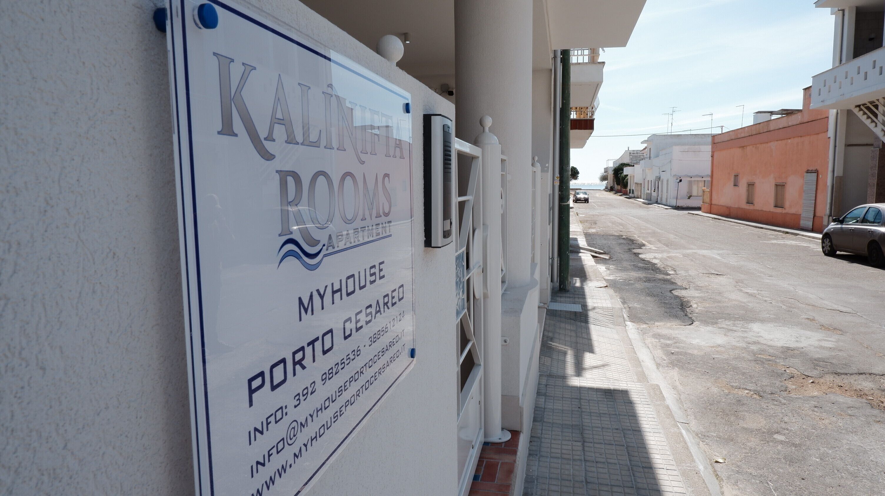 Un letrero que indica 'Kalifia Rooms' con información de contacto y una dirección web.