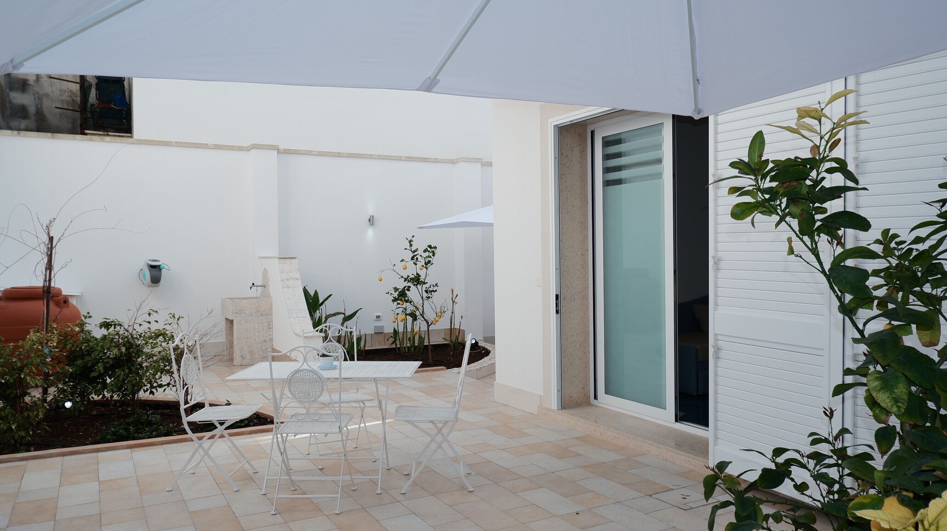 A patio with a table and chairs, a water fountain, and potted plants.