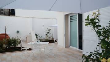 A patio with a table and chairs, a water fountain, and potted plants.