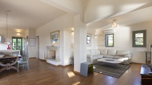 Uma sala de estar espaçosa com lareira, área de jantar com mesa e cadeiras, e um sofá moderno.