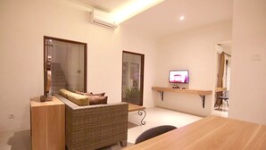 A modern living room with a sofa, a wooden coffee table, and a television on a stand. - Anza d'Dimmel Jimbaran (Jimbaran)
