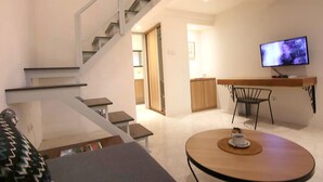 A modern living room with a staircase, a dining area with a TV, and a kitchen in the background. - Anza d'Dimmel Jimbaran (Jimbaran)
