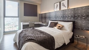 Un dormitorio moderno con una cama grande, un escritorio y vistas a la ciudad.