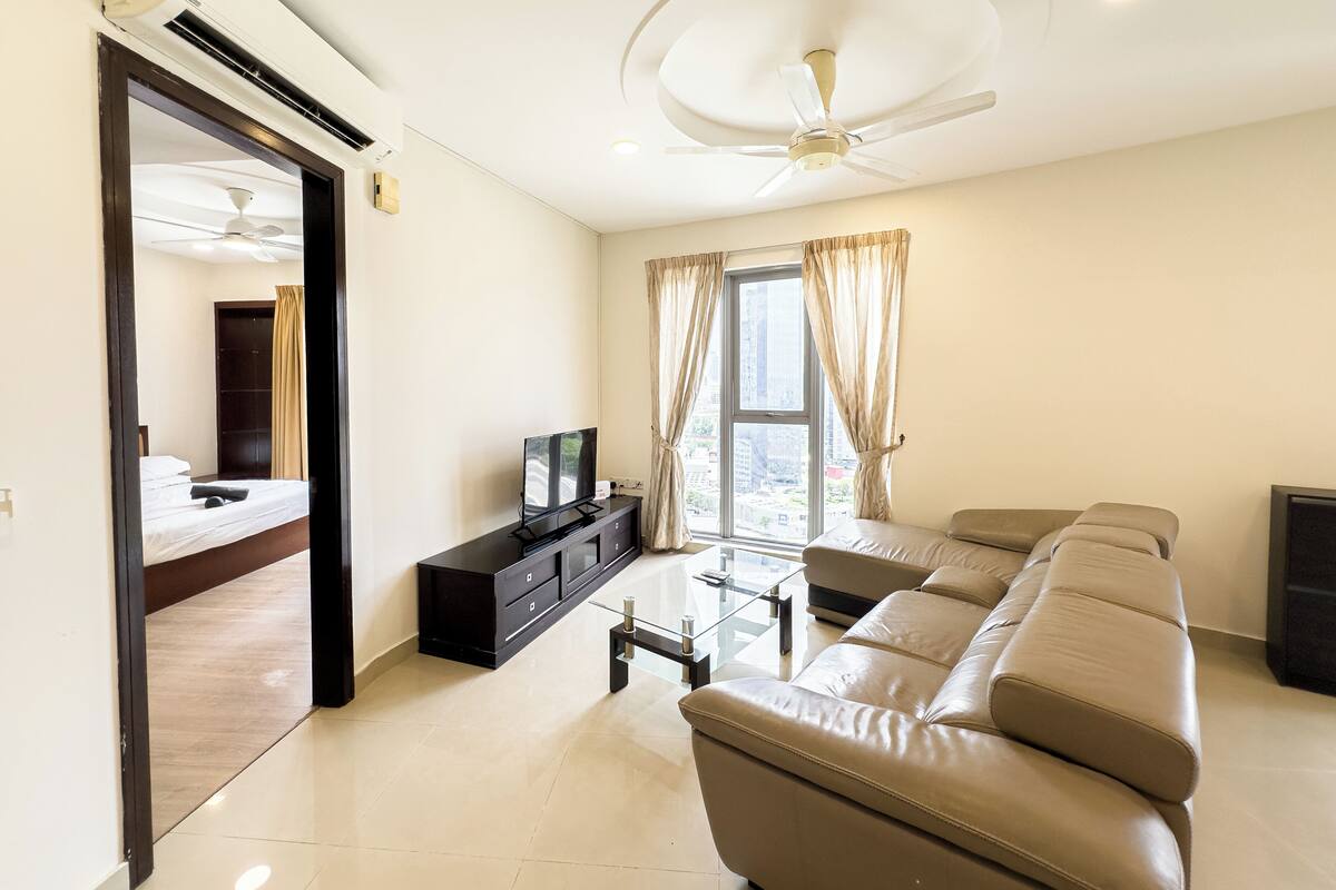A modern living room with a sofa, TV, and a glass coffee table.