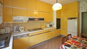 Una cocina con gabinetes amarillos, un microondas blanco y una estufa.