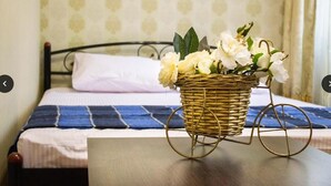 A bed with a blue and white striped bedspread, a white pillow, and a wicker basket with white flowers on a wooden table. - Hostel Koleso (Odesa)