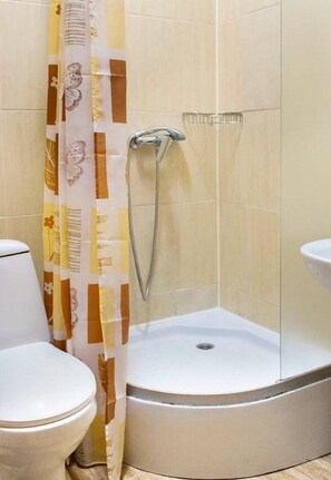 A corner bathroom with a shower, toilet, and sink. - Hostel Koleso (Odesa)