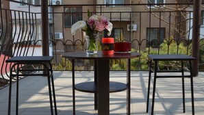 A balcony with a round table, two chairs, a vase with flowers, and a candle. - Hostel Koleso (Odesa)