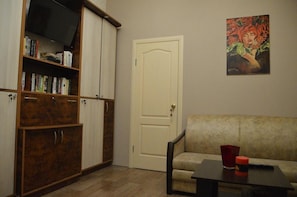 A living room with a sofa, a coffee table, and a bookshelf. - Hostel Koleso (Odesa)