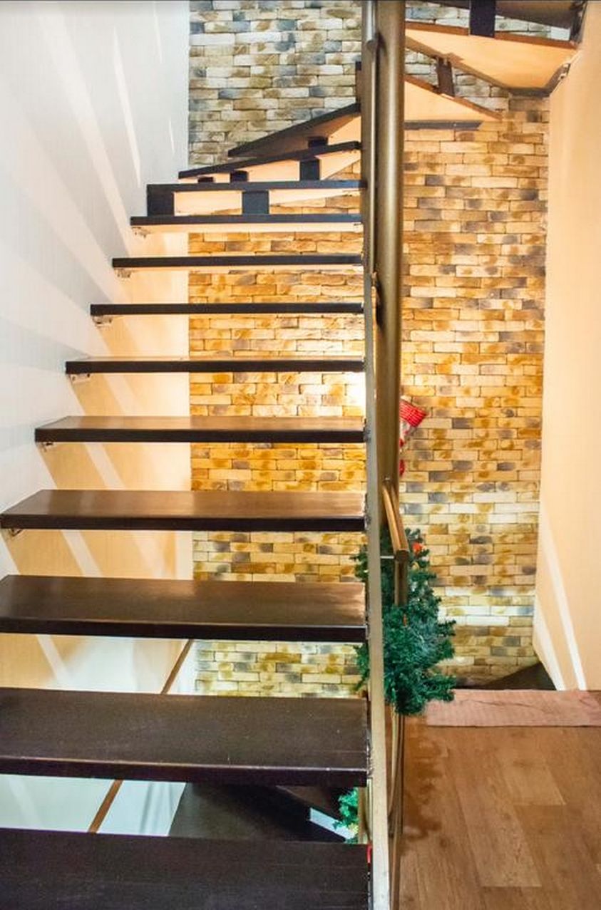 A staircase with a stone wall background and a metal handrail.