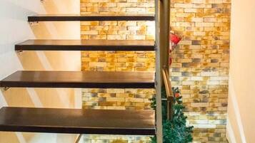 Una escalera con un muro de piedra de fondo y una barandilla de metal.