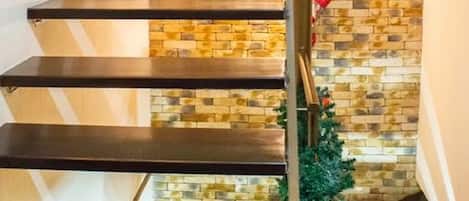 Una escalera con un muro de piedra de fondo y una barandilla de metal.