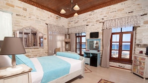 A bedroom with a bed, bedside table, lamp, dresser, and a view of the sea through a window. - 1922 Hotel (Foça)