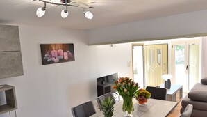 Ein Essbereich mit einem langen Tisch, Stühlen, einem Deckenventilator und einem Fernseher.