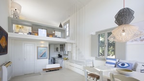Un espace de vie moderne à aire ouverte comprenant une cuisine, un coin repas et une chambre en mezzanine.