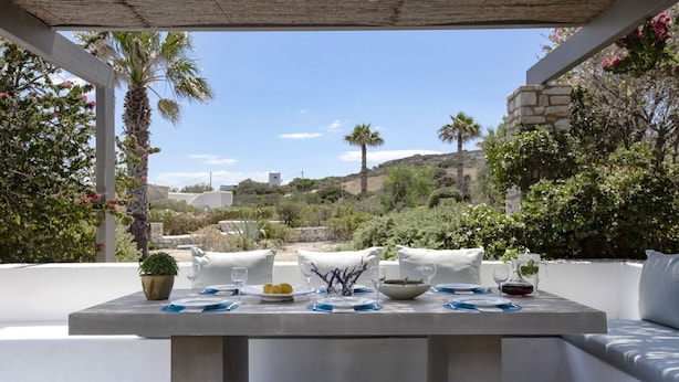 Un espace de restauration en plein air avec une table dressée pour deux personnes, entouré de verdure et offrant une vue sur les collines.